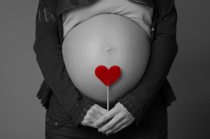 pregnant woman holding heart over stomach